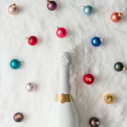 Champagne bottle in snow with colorful Christmas baubles