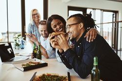 Multi-ethnic group of colleagues enjoying a pizza party in a bright modern office