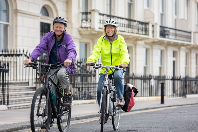 Two older people cycling through British town