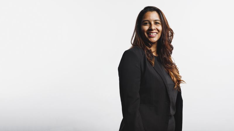 Side view of smiling businesswoman standing against neutral background looking at camera