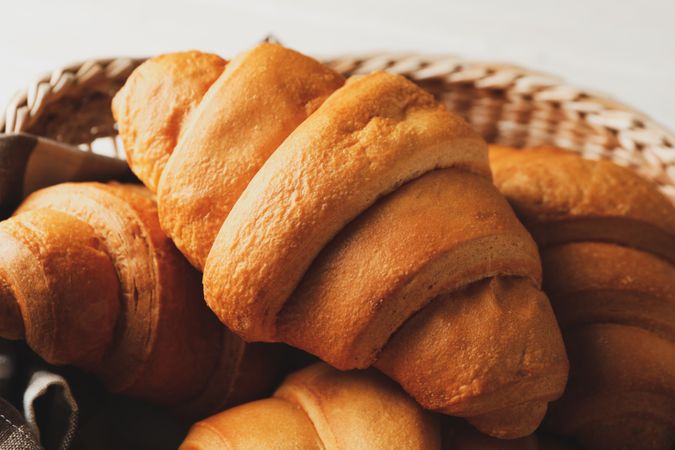 Basket with delicious baked croissants, close up