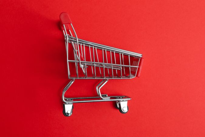 Blank shop trolley on red background, close up