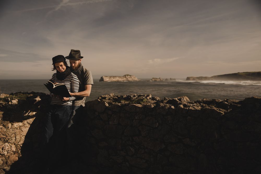Man near woman with books near stones on shore