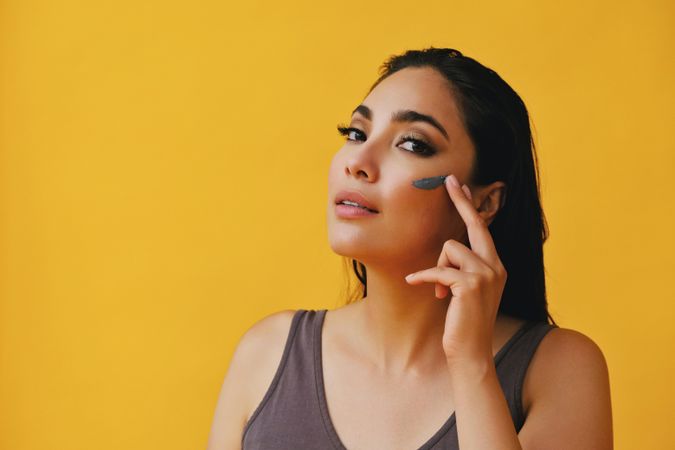 Latina woman applying clay mask with hand, copy space