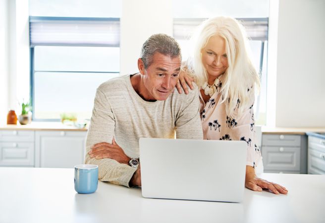 Older couple on a video call together on a laptop in their kitchen