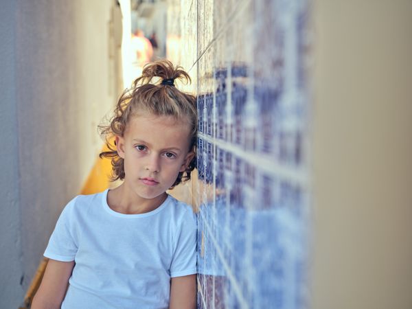 Boy leaning on wall in narrow passage