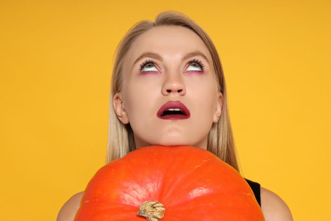 A woman in a Halloween costume with a pumpkin in her hands