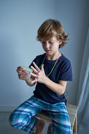 Boy in pajama playing with colorful finger rope