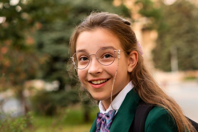 Smiling young girl wearing glasses and school uniform