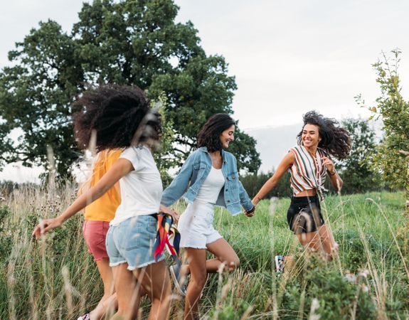 Four happy women in holding hands together in a field