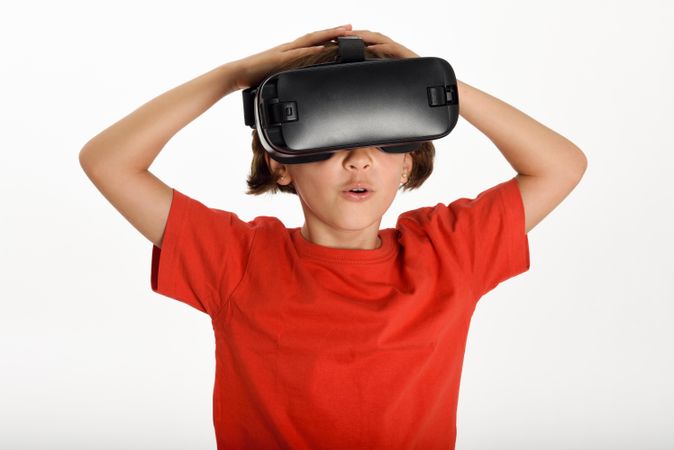 Little girl looking in VR glasses with hands on head