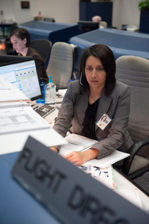 Flight director Ginger Kerrick monitors controllers on console in mission control