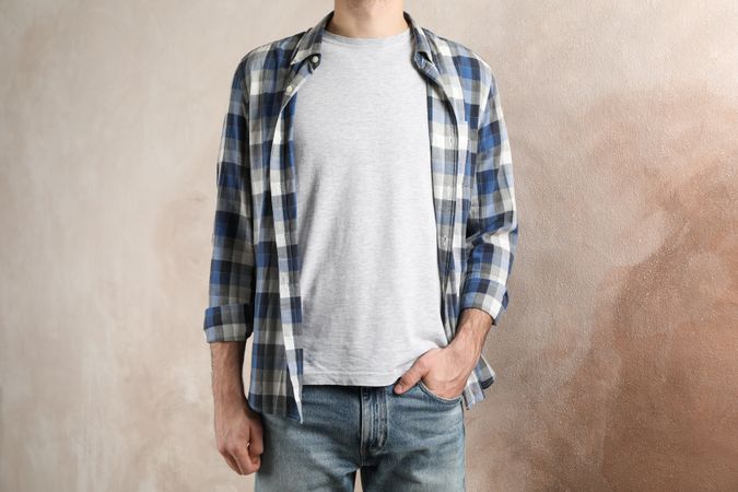 Men in grey t-shirt and checkered shirt against brown background, copy space