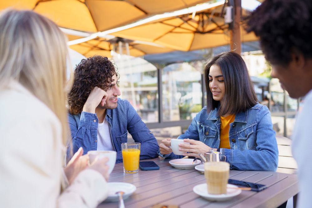 Man and woman chatting at an outside table with friends