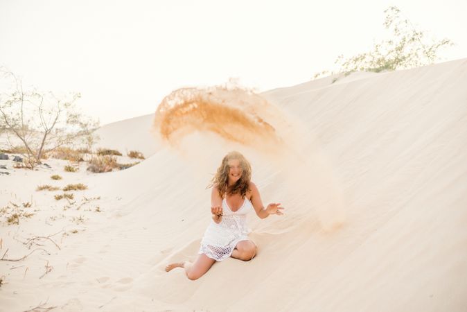 Woman having fun throwing sand in desert