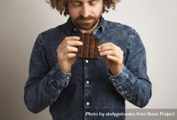 Man looking at chocolate bar he is holding 5wl2A4
