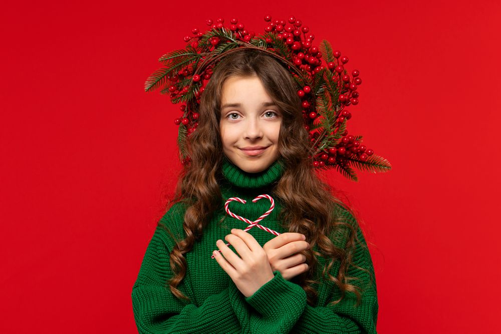 Girl in green sweater holding two candy canes