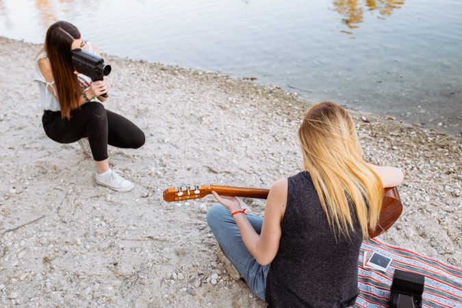 Young woman shooting friend playing guitar