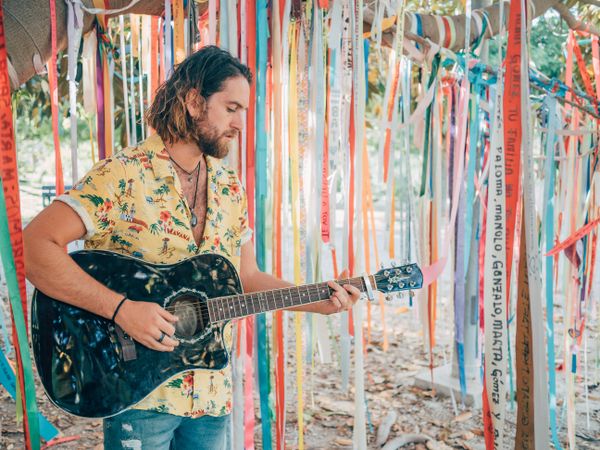 Man playing guitar under decorated tree