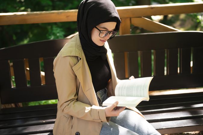 Woman reading while sitting on a park bench