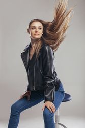 Blonde woman with leather jacket posing in studio