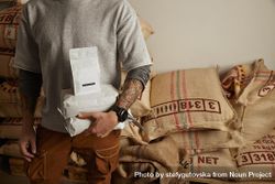 Tattooed barista holds blank package bags with freshly baked coffee beans 0v8e74
