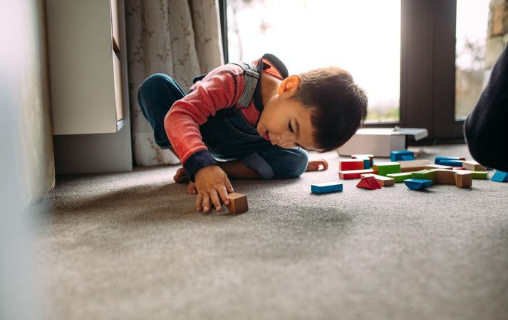 Kid playing on the floor with toys at home