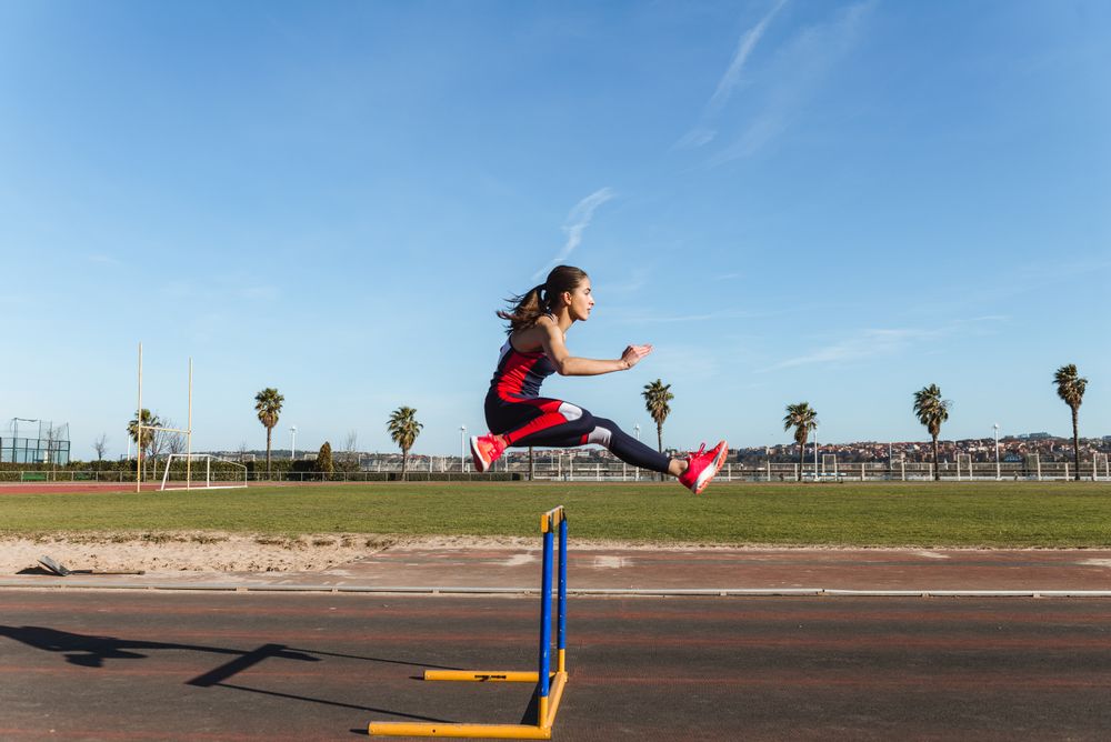 Female athlete hurdling on stadium