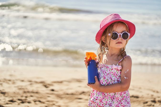 portrait of a girl with a bottle of sunscreen on the beach