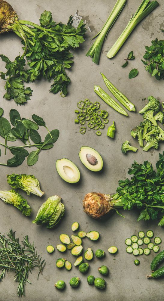 Arrangement of fresh green sliced garden vegetables on concrete surface