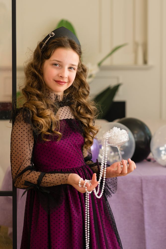 Girl holding pearls and smiling at birthday celebration.