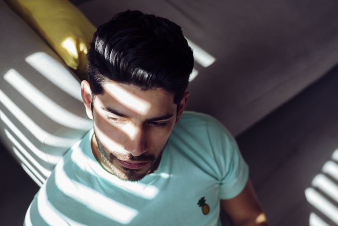 Young sad man sitting on couch at home