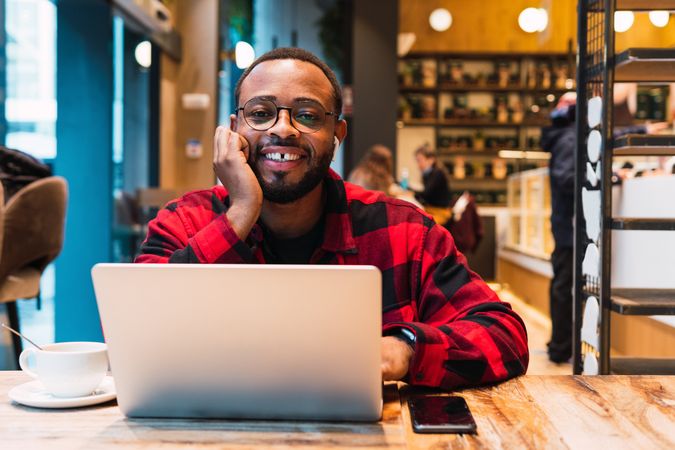 Smiling Black man working on laptop in cafe