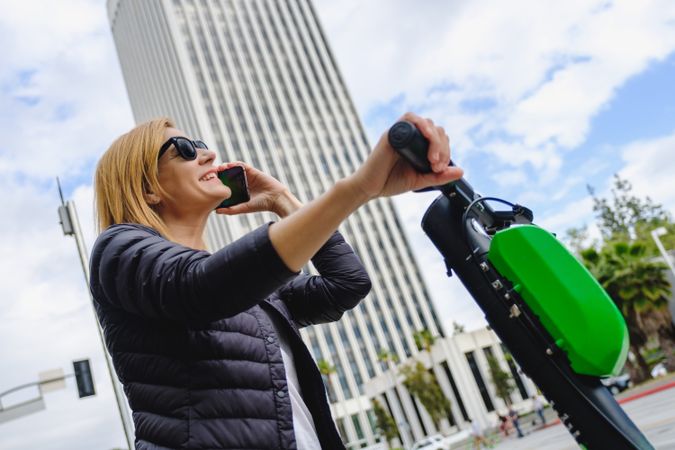 Woman talking on smartphone and riding electric scooter