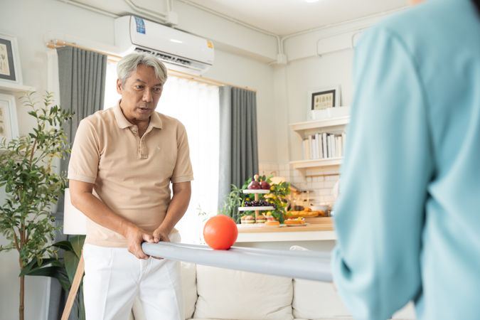 Older man playing rolling ball for practice balance and concentrate at home