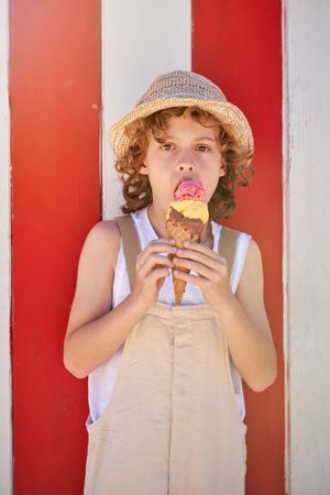 Boy with curly hair licking ice cream