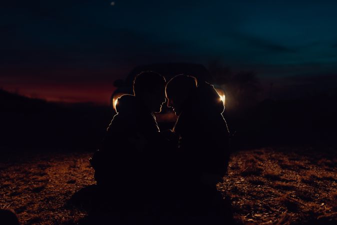 Men hugging and sitting on ground on field at night