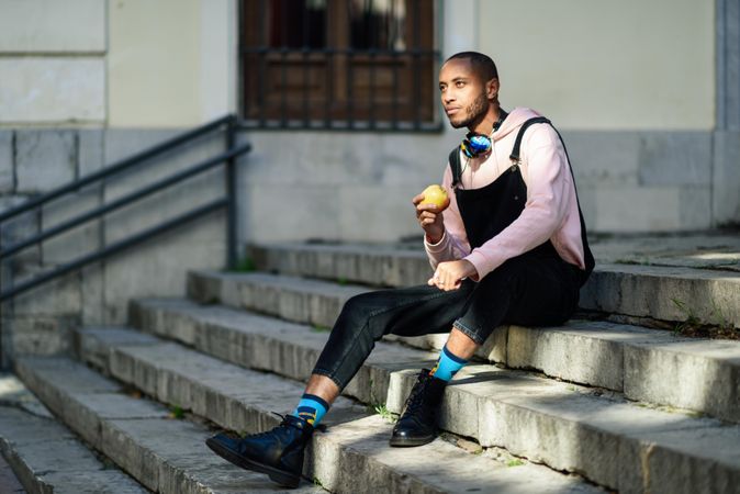 Calm male in overalls and boots relaxing on outdoor steps