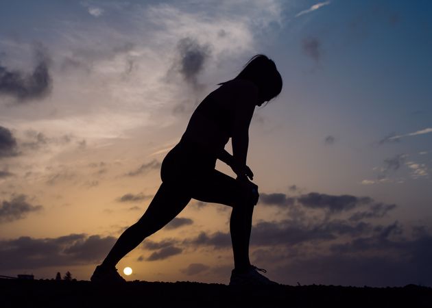 Stretching woman and sky with clouds at sunset