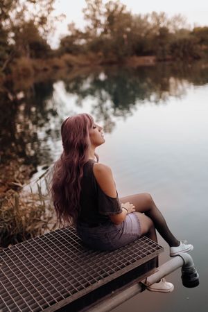 Stylish modern woman sitting on metal pier