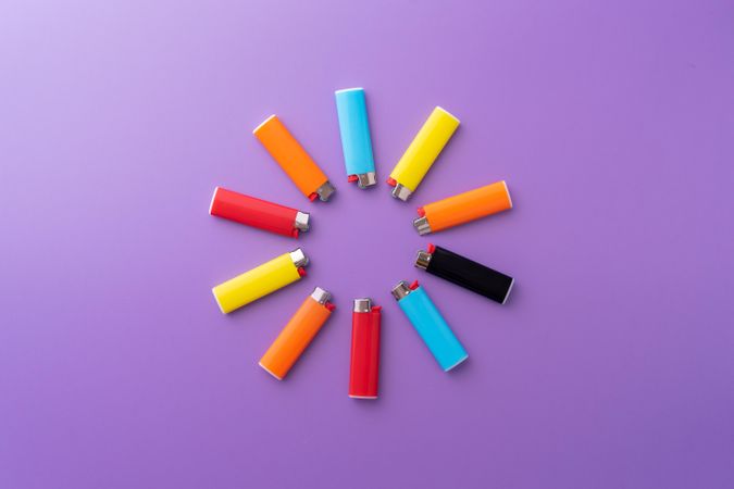Colorful lighters in a circle shape on purple background