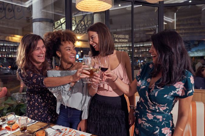 Delighted multiethnic women toasting in restaurant