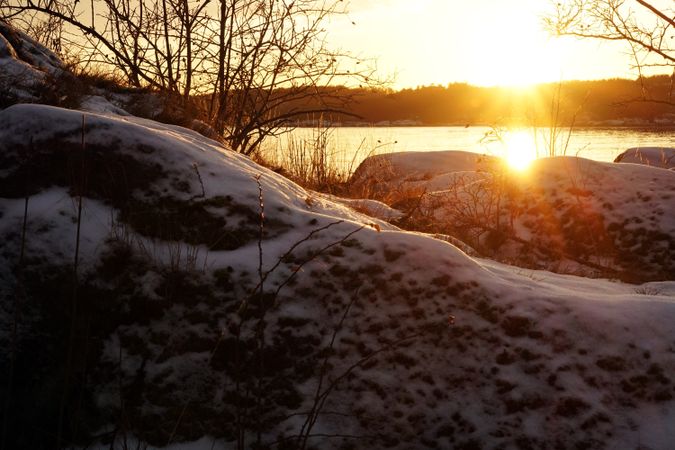 Rocky peaceful shore with snow crust in sunrays