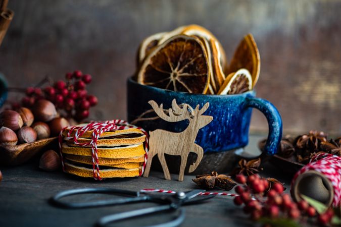 Blue mug with dried orange slices with reindeer ornament and hazelnuts