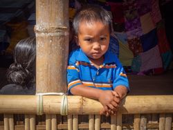 Sulawesi Island, Indonesia - August, 15 2015: Frowning kid on bamboo terrace in village