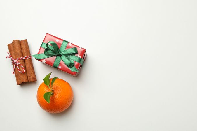 Mandarin, cinnamon and gift box on light background