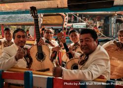 Smiling mariachi band on boat in river in Mexico 56AjY0