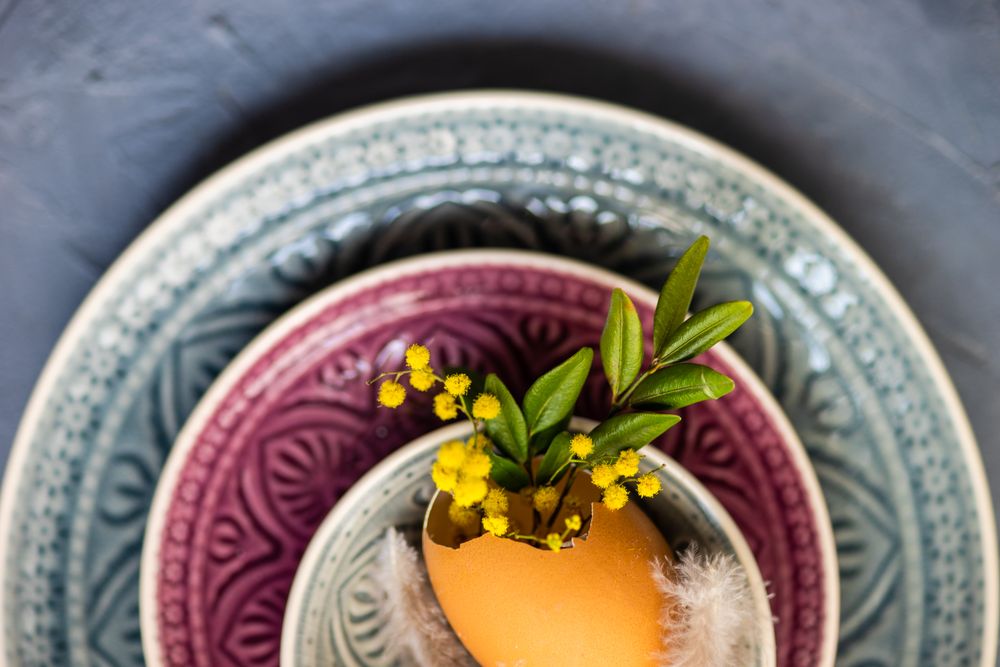 Top view Easter table setting with egg and foliage on patterned plates