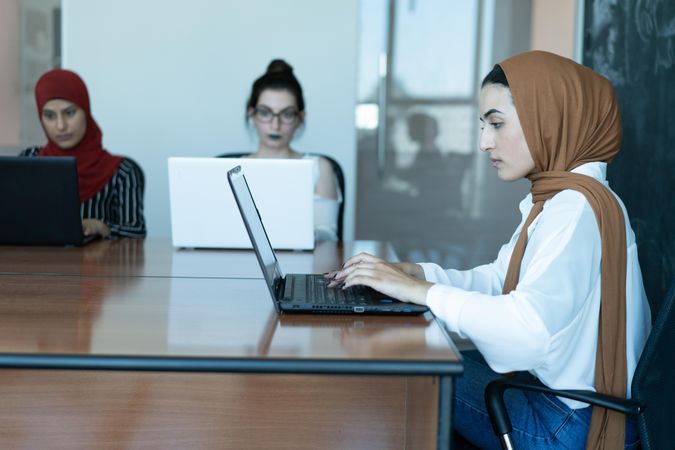 Three women working together on their laptops in an office