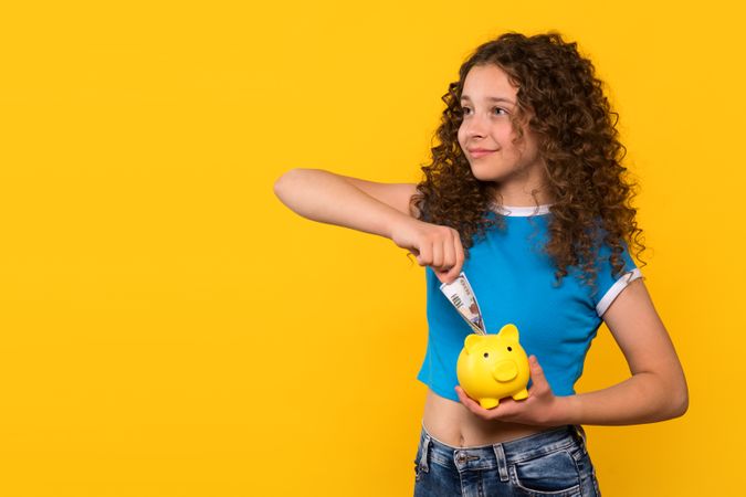 Girl putting money into piggy bank